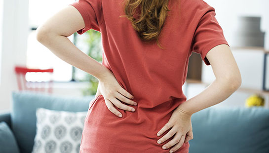 Woman holding lower back in pain before visiting Akron chiropractor