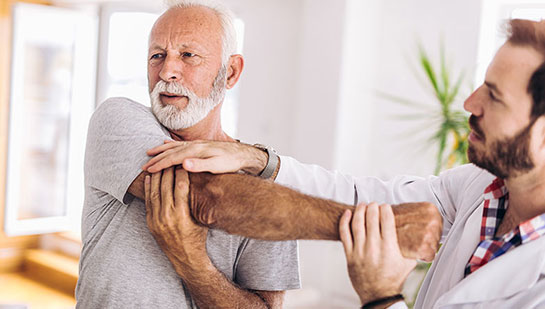 Elderly man receiving shoulder adjustment from Akron chiropractor